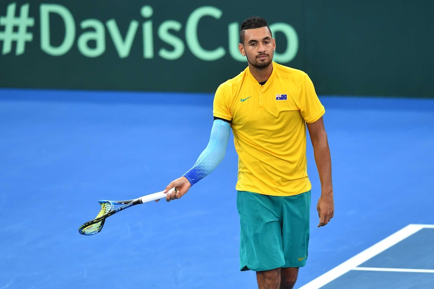 Nick Kyrgios walks off the court with a broken racquet.