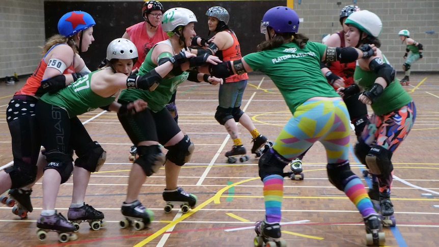 Derby players push against each other while on skates.