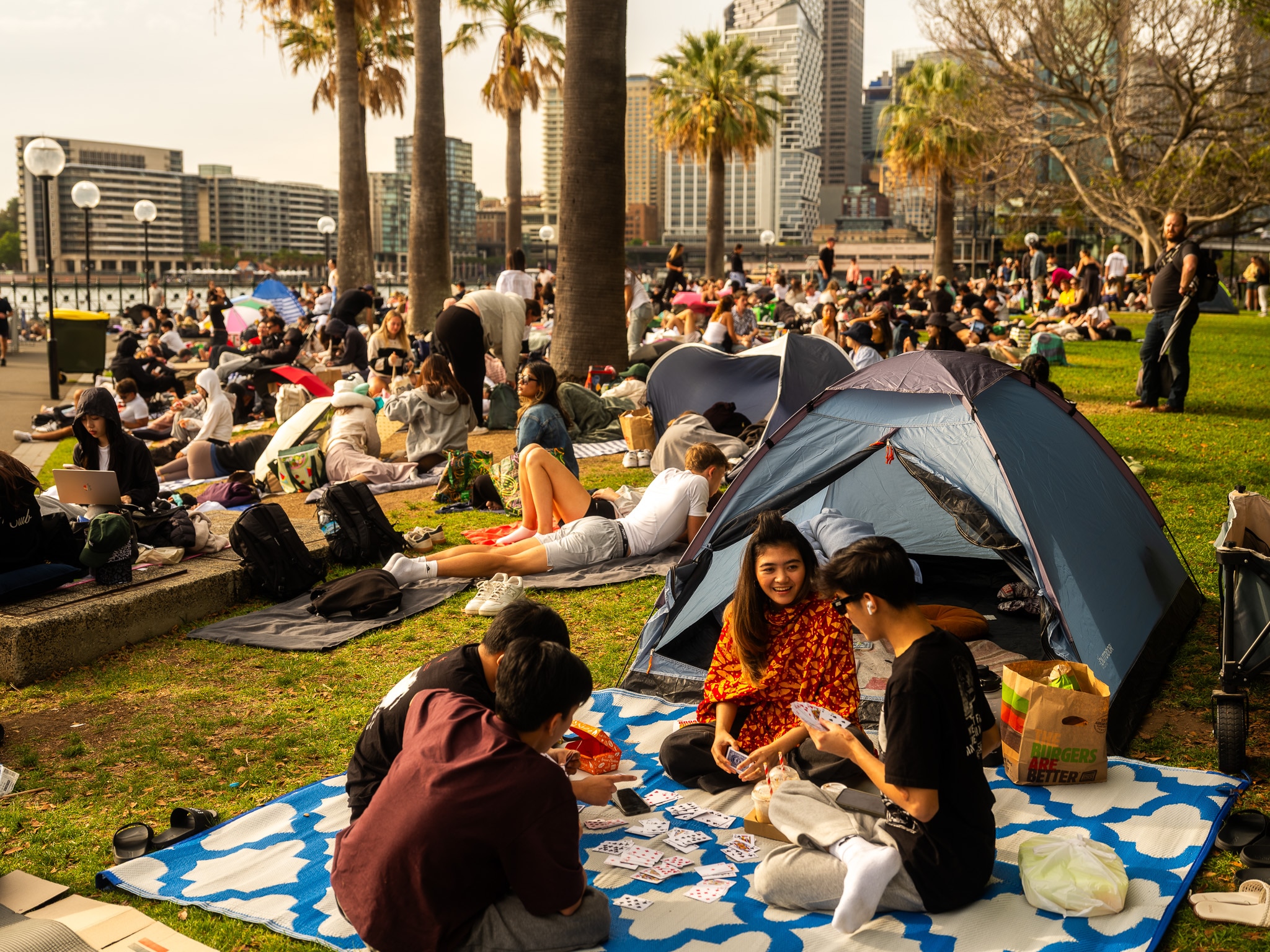 Personas frente a una tienda de campaña y otras sentadas en el césped en Sydney.
