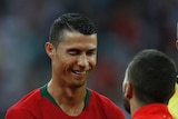 Ronaldo winks and smiles at an opposition player.
