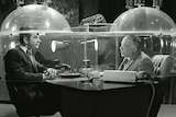 A black and white photo from TV show Get Smart showing two men sitting inside a plastic cone.