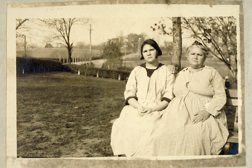 Carrie and Emma Buck sitting side by side on a park bench.