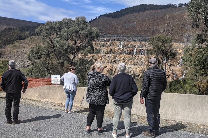 group watching water coming down a rock-fill embankment dam 