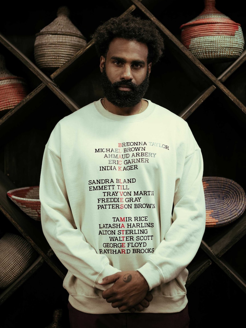 A man stands in front of a shelf with baskets on it.