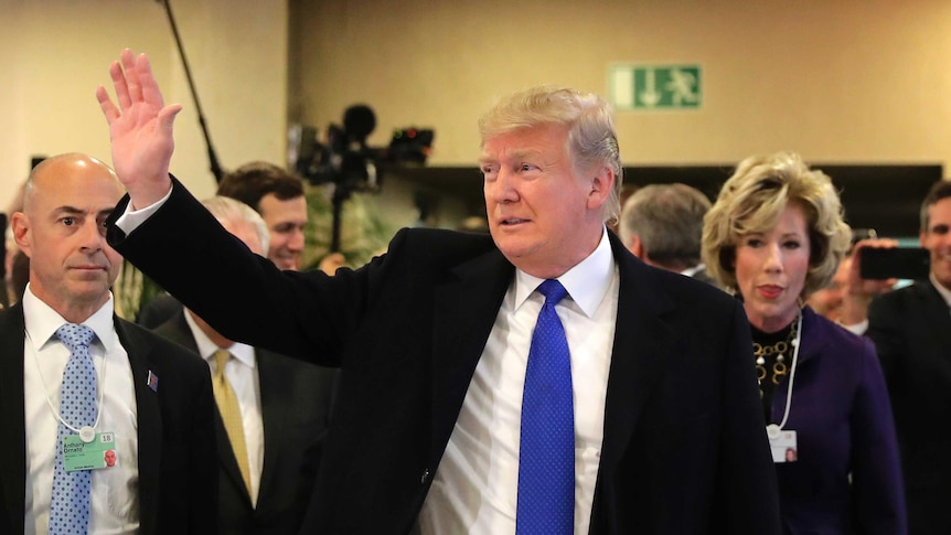 Donald Trump walks among staff and waves as he arrives at the World Economic Forum in Davos.