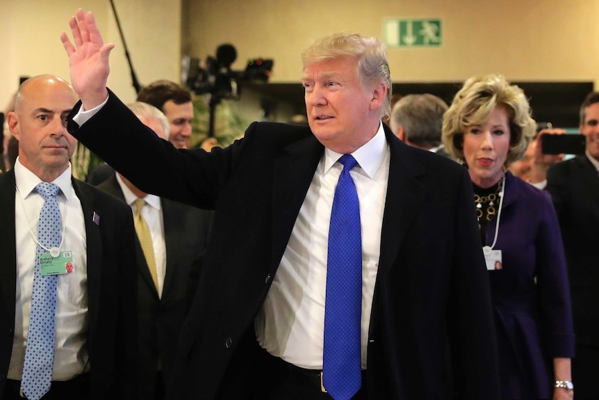 Donald Trump walks among staff and waves as he arrives at the World Economic Forum in Davos.