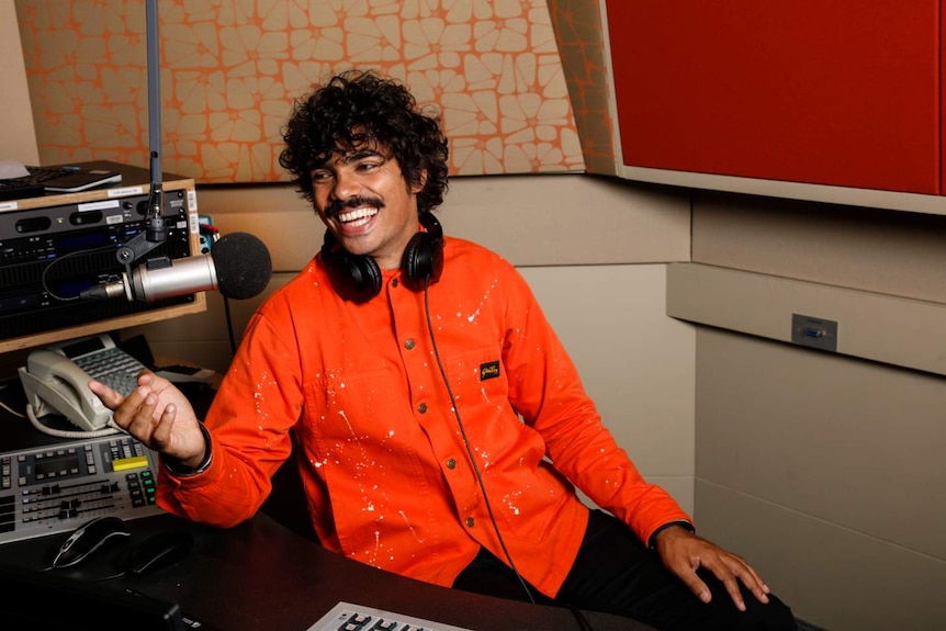 Man sitting behind a microphone in a radio studio.