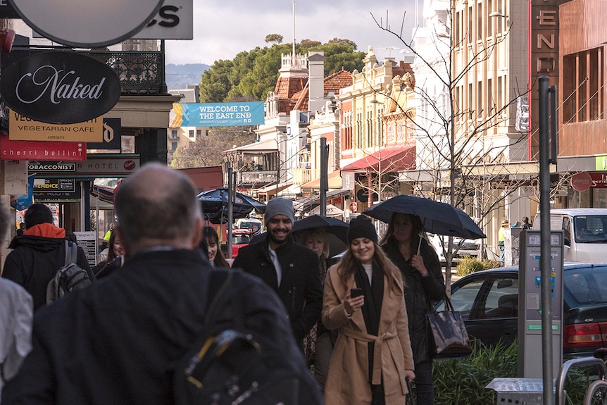 People walk along Rundle Street laughing.