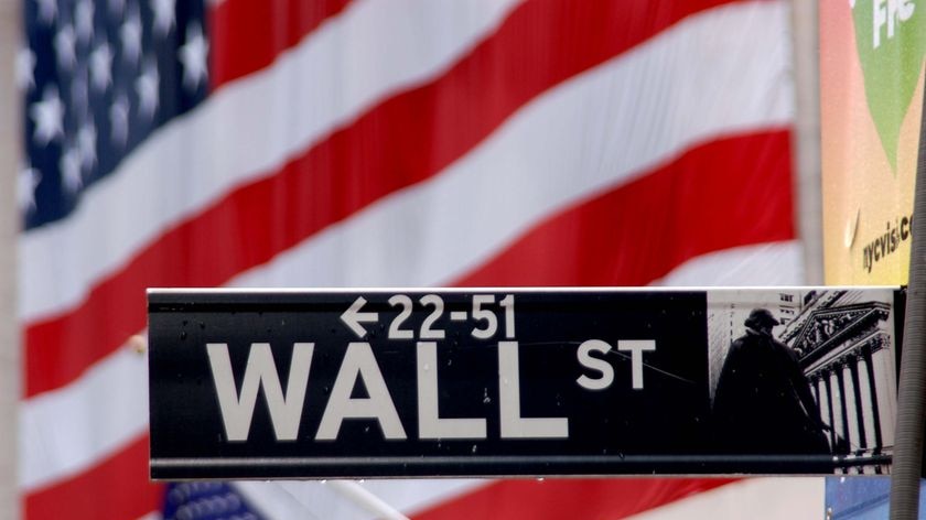 Wall Street sign with the American flag on the New York Stock Exchange behind