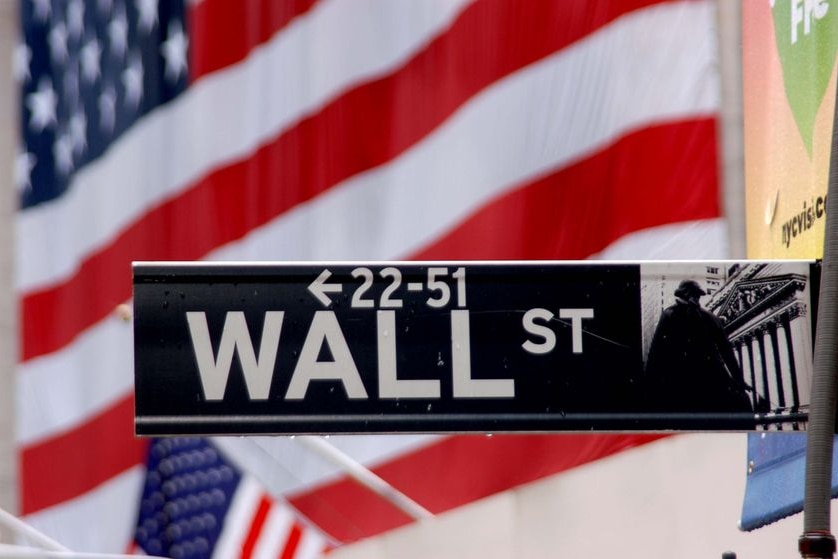 Wall Street sign with the American flag on the New York Stock Exchange behind