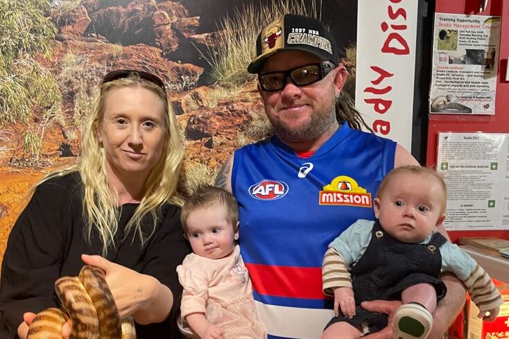 Jarrod holds baby twins Shakira and Bodhi, standing next to Chrissy who holds a snake.