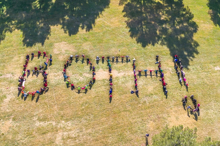 Aerial shot of people standing to form the word Both