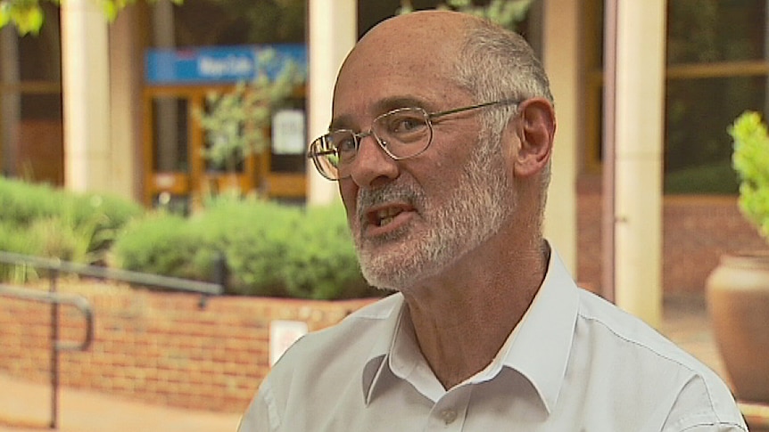 A bald man with a beard wearing a white shirt