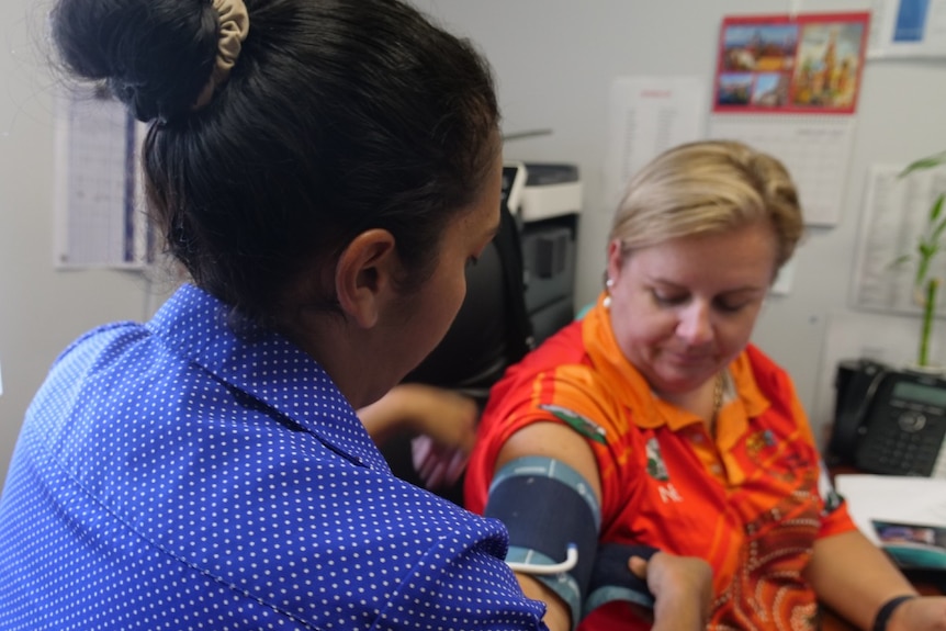 Dani Beezley, back to the camera, putting a blood pressure cuff on a patient.