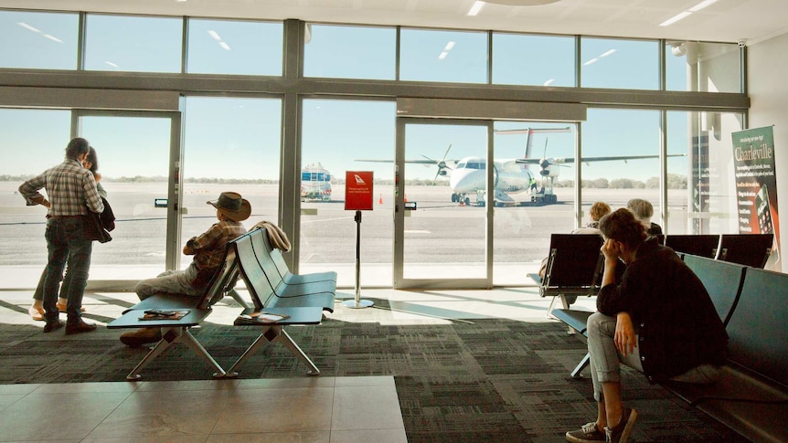Taken from inside the terminal, passengers look out to a plane on the tarmac.