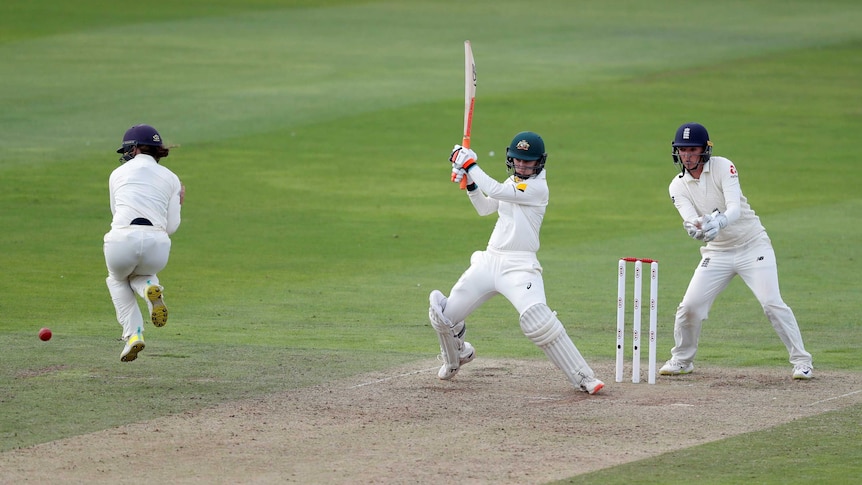 A women's cricketer crashes the ball away on the on-side, forcing a close fielder to jump away.
