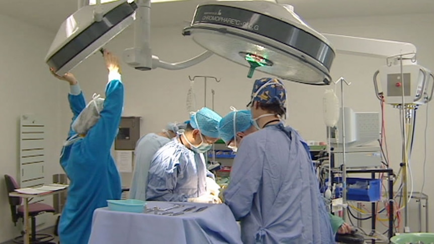 Surgeons and nurses perform an operation at a hospital in Canberra.