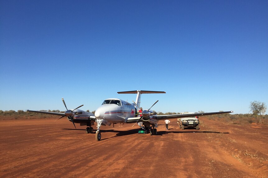 An RFDS plane landed on red dirt with a blue sky in the background.