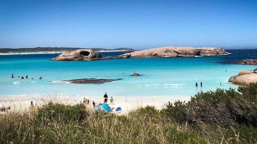 Twilight beach is pictured on a sunny day, with quite a few people swimming and at the beach