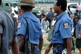 Armed Papua New Guinea police walk past an agitated crowd following a disturbance at Koki Market
