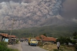 People watch as Mount Sinabung spews volcanic ash behind them.