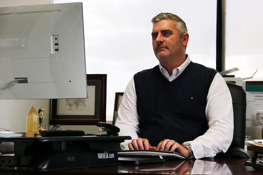 A man sitting at a desk, typing on a computer keyboard