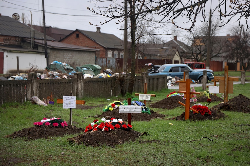 Graves sit behind private houses in Mariupol