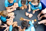 New prep-aged children sit on floor in circle in prep classroom playing barrel of monkeys game