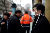 A tourist wears a protective mask in front of the Galeries Lafayette department store.