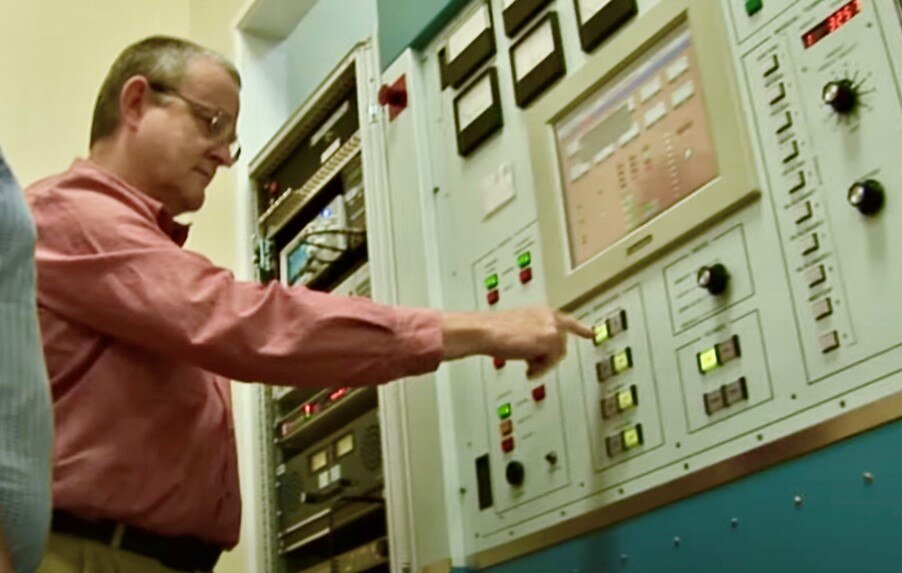 Man pushes button on large audio equipment panel.