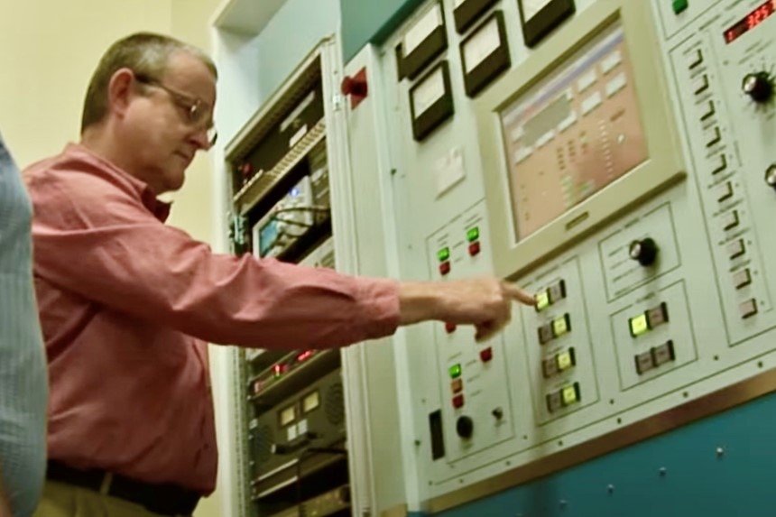 Man pushes button on large audio equipment panel.
