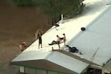 Residents in the Lockyer Valley sit on a roof as flash floods sweep through on January 10, 2011.