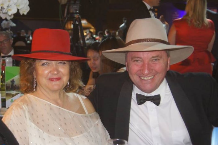 Gina Rinehart, wearing a red akubra, sits next to Barnaby Joyce, wearing his usual tan akubra, at a dinner.