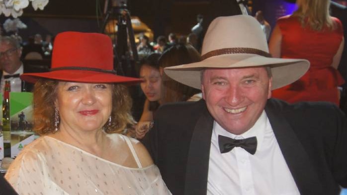 Gina Rinehart, wearing a red akubra, sits next to Barnaby Joyce, wearing his usual tan akubra, at a dinner.