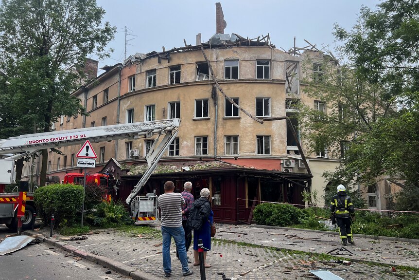 people standing infront of the destroyed building in Lviv with a crane infront
