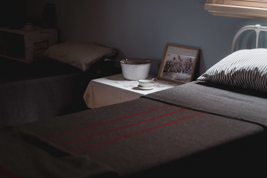 Old hospital room with beds and table.