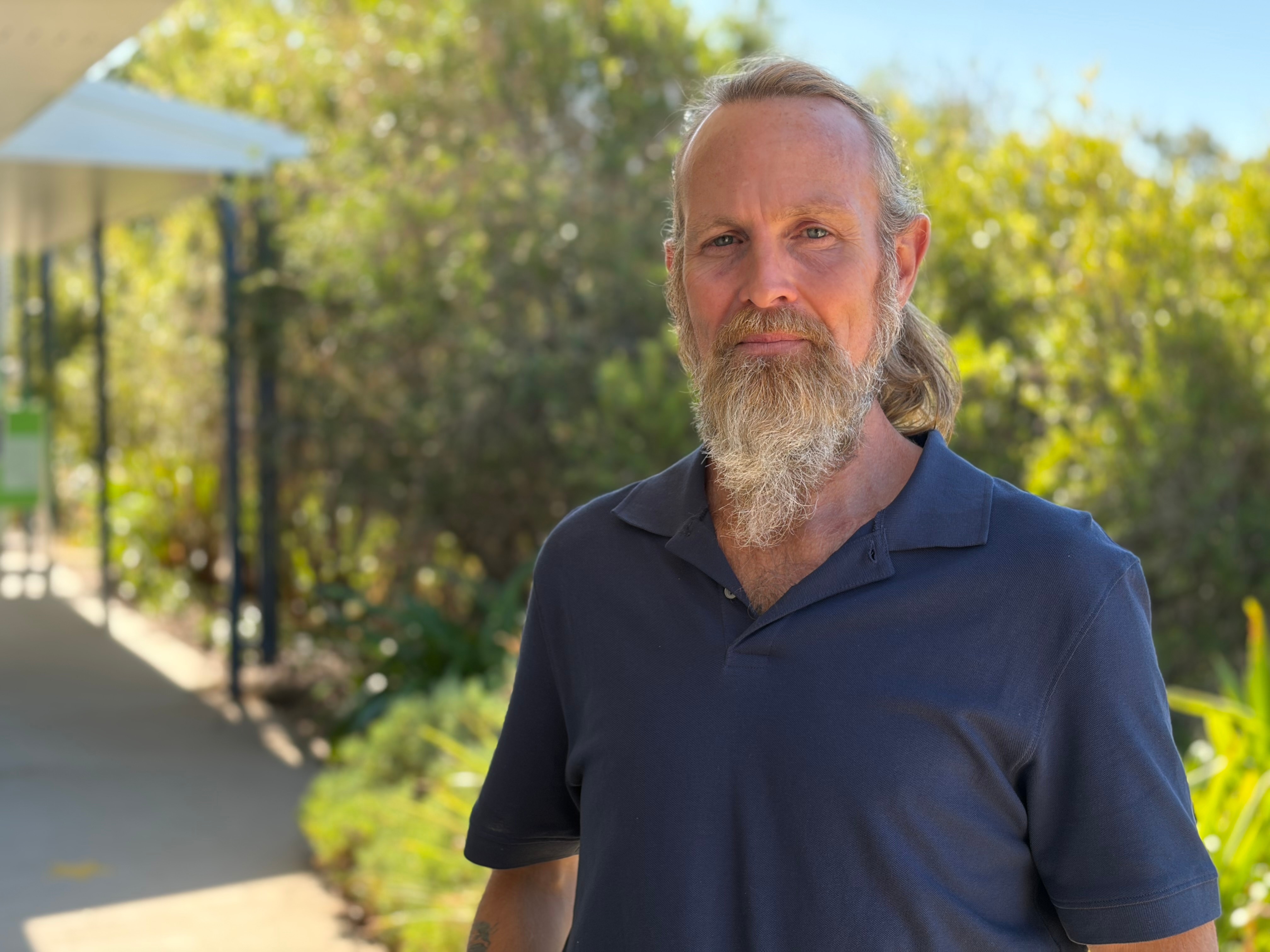 A man with long hair and a beard with a pathway behind him