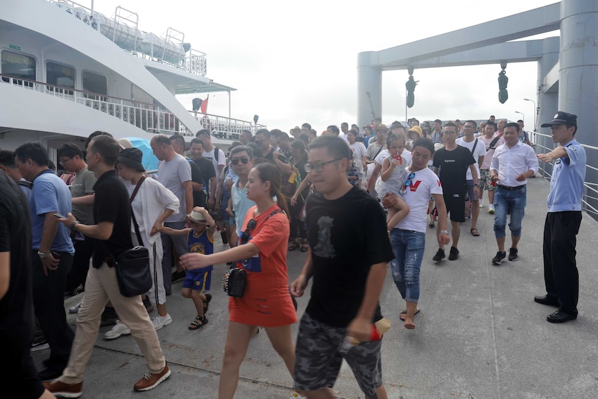 Chinese police are escorting hordes of tourists off cruise boats ahead of the typhoon arriving.
