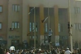 Massacre: Protesters climb flag poles in front of Libya's internal security headquarters in Benghazi.