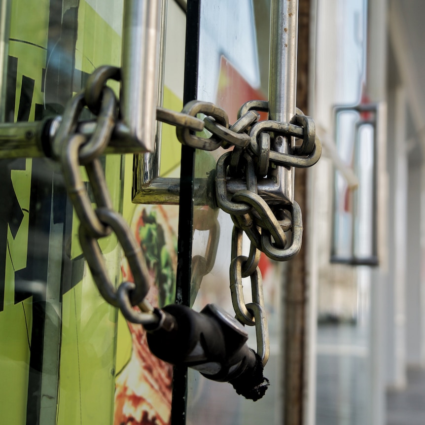 A chain and lock secure the front door of a shop.