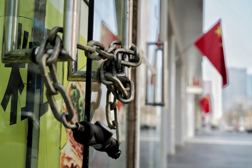 A chain and lock secure the front door of a shop.