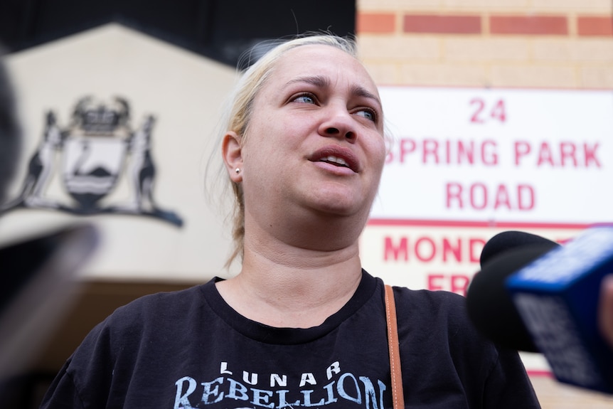 A blonde woman looks distressed as she is pictured outside a courthouse