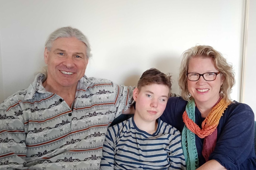 A man and a women sit with a 14-year-old boy between them.