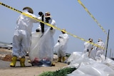 Health, Safety and Environment workers place part of an oil snare boom into bags