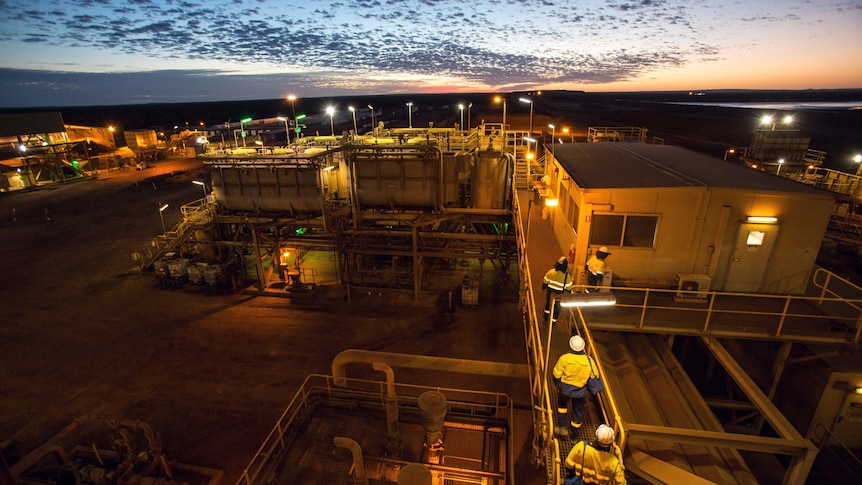 Workers walking next to dongas at sunset.