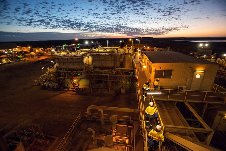 Workers walking next to dongas at sunset.