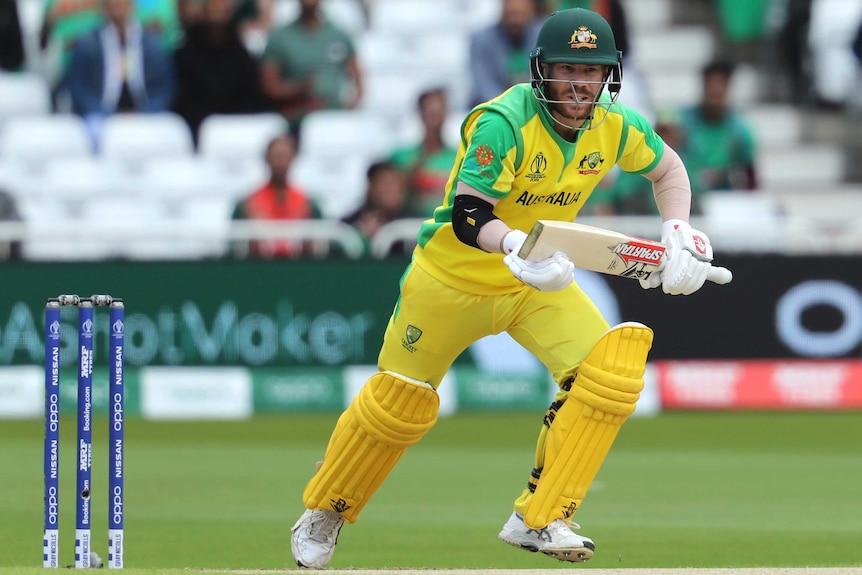 David Warner sets off for a run holding his bat in front of his body with a hand at each end