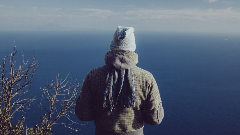 Photo of a man looking out to sea wearing a beanie