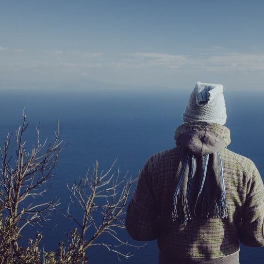 Photo of a man looking out to sea wearing a beanie