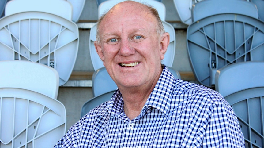 A portrait of Geoff Mann in a sports stadium grandstand